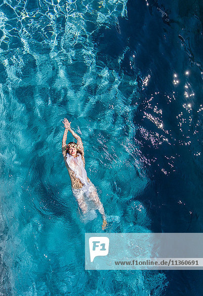 Overhead view of woman swimming on back in swimming pool