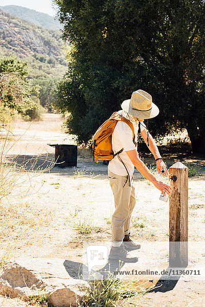 Mann füllt Wasserflasche am Wasserhahn im Freien  Malibu Canyon  Kalifornien  USA