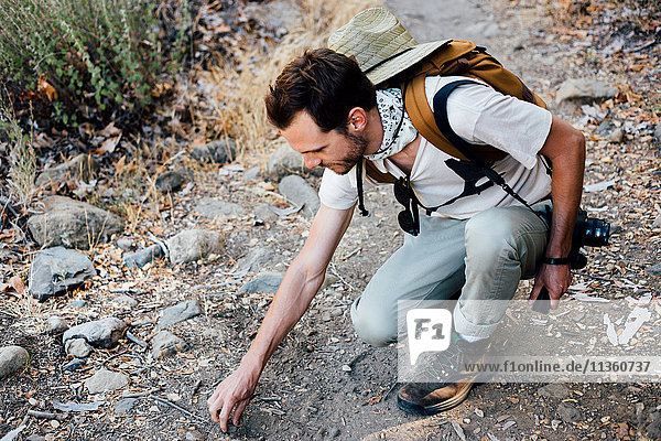 Hiker crouching picking up stones  Malibu Canyon  California  USA