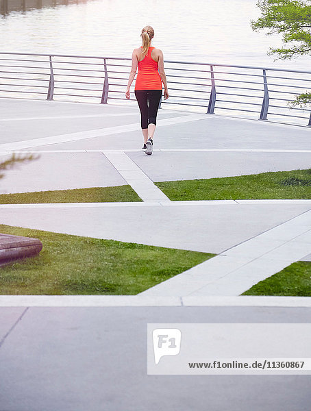 Rückansicht einer Frau in Sportkleidung auf einem städtischen Landschaftsbild