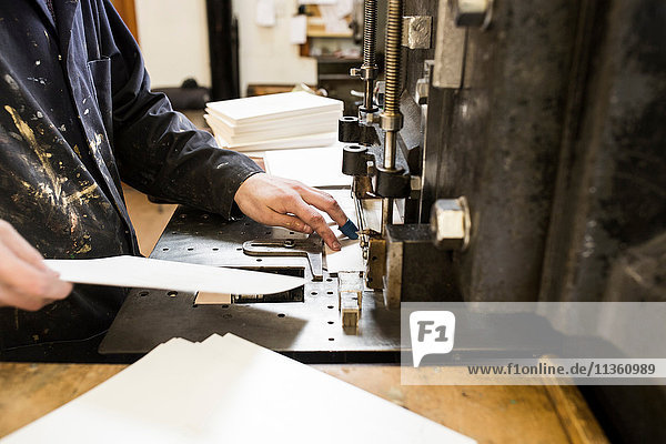 Männlicher Drucker bereitet Papier für Druckmaschinen in der Druckmaschinenwerkstatt vor