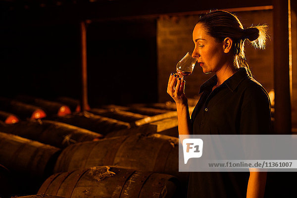 Weibliche Verkosterin riecht Whisky im Glas in der Whisky-Destillerie