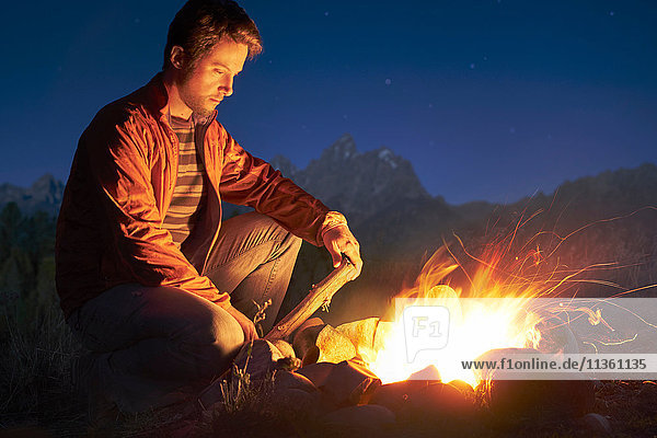 Man crouching by campfire at night Jackson Wyoming USA