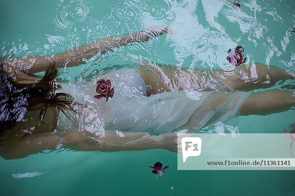 Blick von unten auf eine Frau  die mit Orchideen unter Wasser im Schwimmbad des Heilbades schwimmt