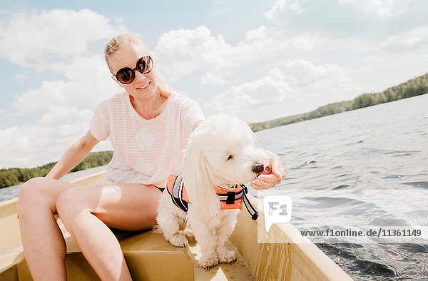 Frau streichelt coton de tulear Hund im Boot  Orivesi  Finnland