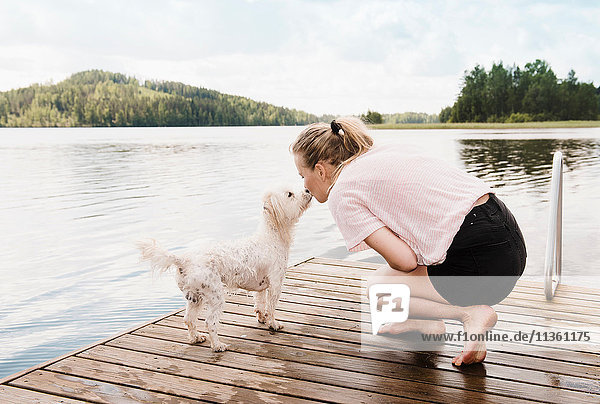 Frau küsst coton de tulear Hund auf dem Pier  Orivesi  Finnland
