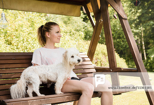 Frau sitzt auf Schaukelstuhl mit coton de tulear Hund  Orivesi  Finnland