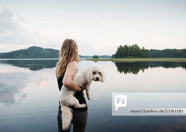 Woman carrying coton de tulear dog at lake  Orivesi  Finland