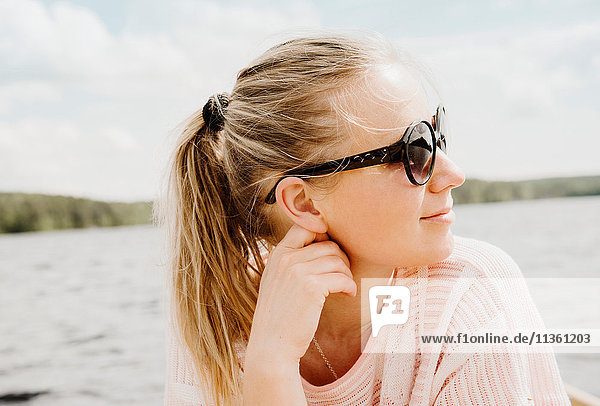 Woman wearing sunglasses looking over her shoulder to lake  Orivesi  Finland