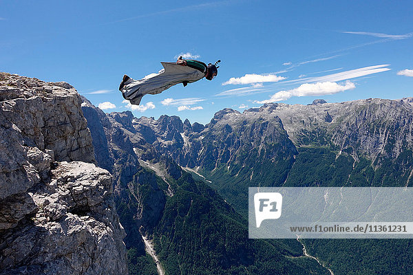 Wingsuit BASE-Jumper fliegt von einer Klippe Italienische Alpen  Alleghe  Belluno  Italien