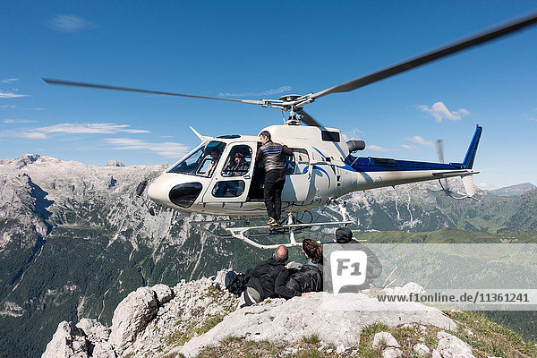 Männliches und weibliches BASE-Sprungteam beim Verlassen des Hubschraubers auf dem Gipfel des Berges Col di Pra  Italienische Alpen  Alleghe  Belluno  Italien