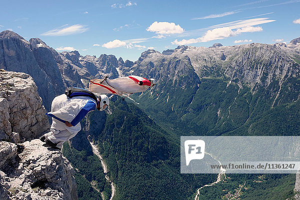 BASE jumping wingsuit pilots are jumping together from a cliff and down the valley  Italian Alps  Alleghe  Belluno  Italy