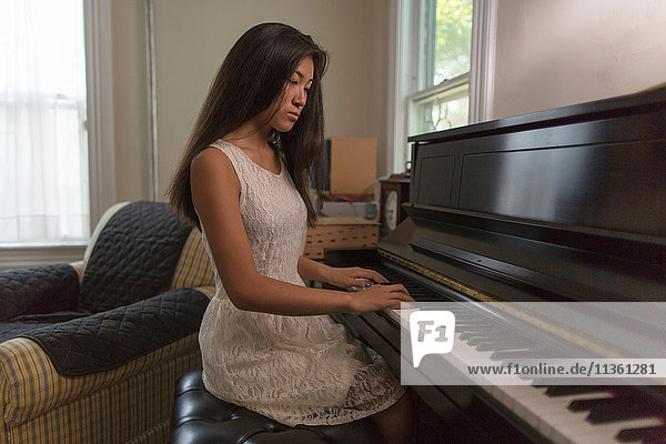 Teenager-Mädchen sitzt im Esszimmer und spielt Klavier