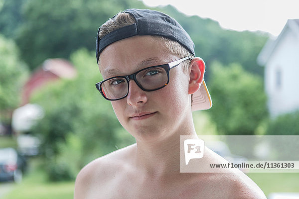 Close up portrait of teenage boy wearing tinted glasses in garden