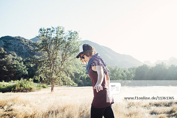 Seitenansicht einer Frau  die im Feld an Bergen entlang geht  Malibu  Kalifornien  USA