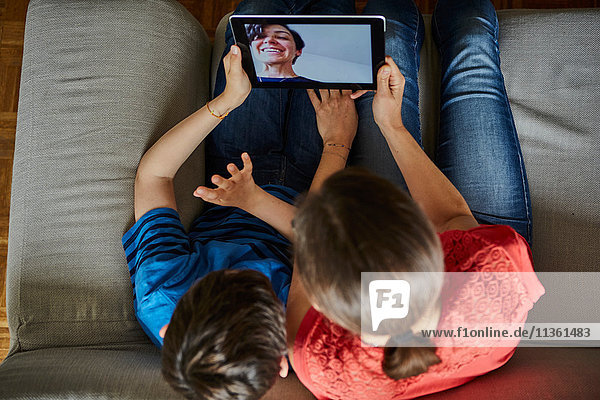 Draufsicht von Mutter und Sohn auf dem Sofa mittels digitalem Tablett