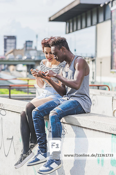 Couple in urban area looking at smartphone  Milan  Italy