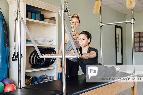Woman and personal trainer using pilates reformer