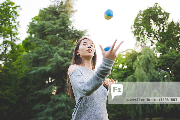Junge Frau im Park jongliert Bälle