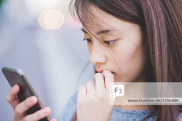 Close up of young woman reading smartphone