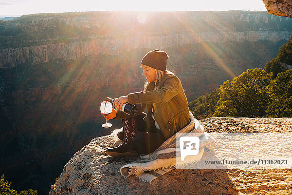 Frau schenkt ein Glas Wein am Rand des Grand Canyon ein  Arizona  USA