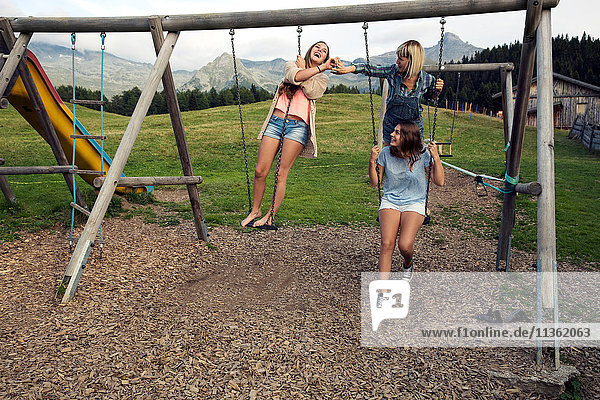 Three female adult friends playing on swings in Austrian Alps  Sattelbergalm  Tirol  Austria