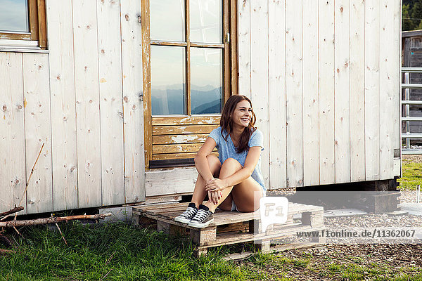 Junge Frau auf Paletten sitzend  Sattelbergalm  Tirol  Österreich