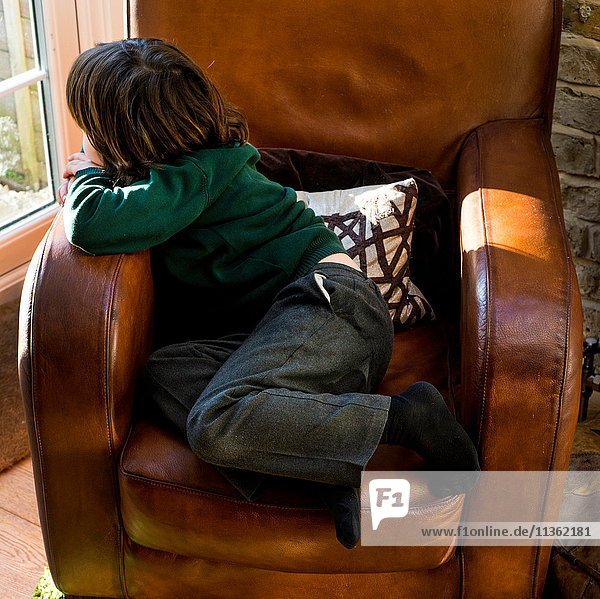 Junge entspannt sich nach der Schule auf einem Sessel