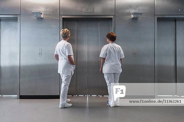 Rear view of nurses in hospital waiting for elevator
