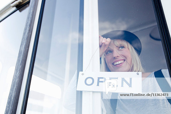 Woman placing open sign on glass door smiling