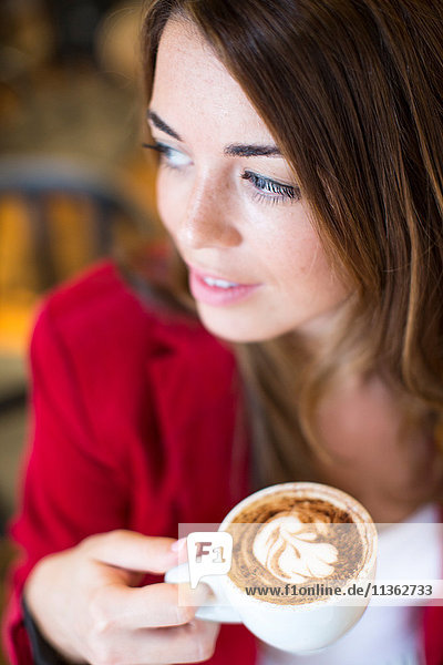 Close up of young woman with cappuccino in cafe
