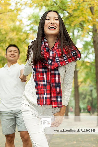 Junge Frau  die ihren Freund im Herbstpark an der Hand zieht  Peking  China