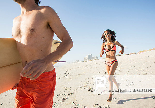 Young surfing couple running down beach  Cape Town  Western Cape  South Africa