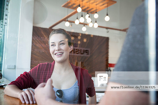 Young woman sitting with man in cafe  smiling