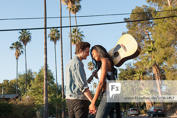 Junges Paar im Freien  von Angesicht zu Angesicht  lachend  junge Frau mit Gitarre