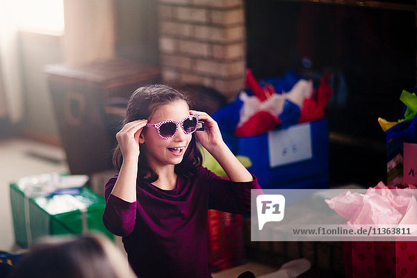 Mädchen eröffnet Geschenke,  probiert eine Sonnenbrille an