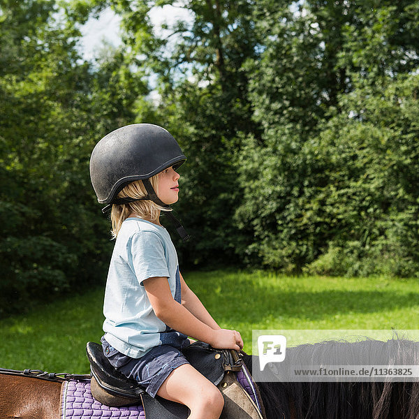 Side view of boy horse riding