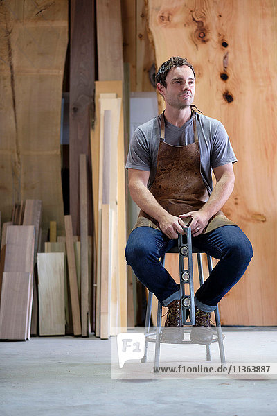 Zimmermann in seiner Werkstatt  mit Holzwerkzeug in der Hand