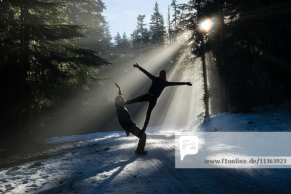 Silhouettes of acrobats in snow covered forest balancing  Frog lake  Mount Hood  Oregon  USA