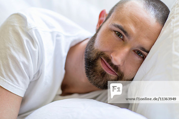 Porträt eines im Bett liegenden Mannes im mittleren Erwachsenenalter