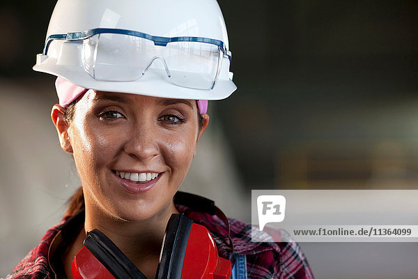 Porträt einer jungen Arbeitnehmerin mit Schutzhelm
