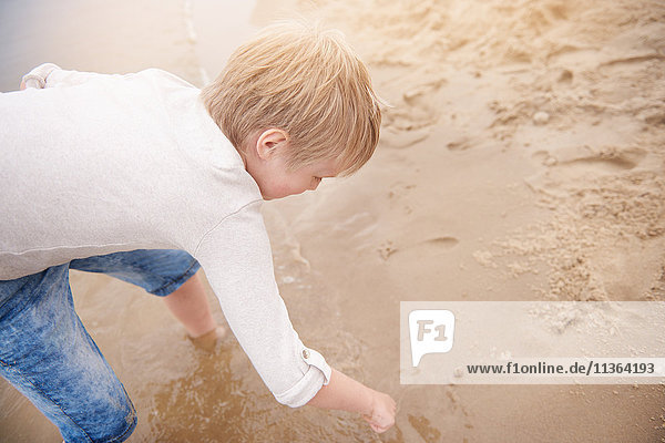 Junge zeichnet im Sand