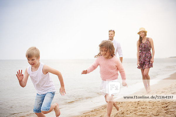 Familie läuft am Sandstrand entlang