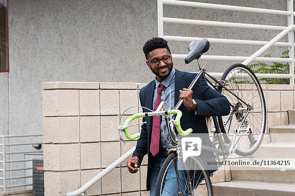 Junger Mann trägt Fahrrad die Treppe hinunter