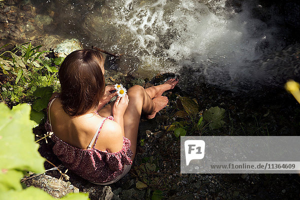 Draufsicht einer am Flussufer sitzenden jungen Frau  Sattelbergalm  Tirol  Österreich