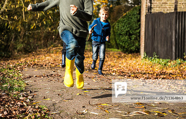 Drei Jungen  die im Herbst den Pfad entlang laufen  niedriger Abschnitt