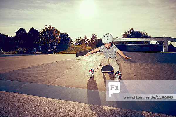 Junge sitzt auf Skateboard im Park