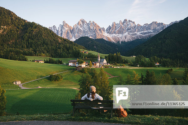 Woman relaxing on park bench  Santa Maddalena  Dolomite Alps  Val di Funes (Funes Valley)  South Tyrol  Italy