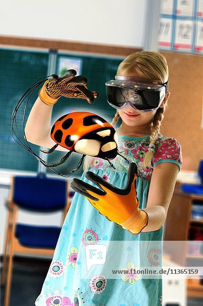 Mädchen  das sich als Lehrerin ausgibt und ein Virtual-Reality-Headset und Handschuhe trägt  um Marienkäfer zu zeigen