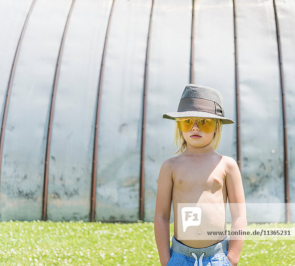 Porträt eines Jungen mit Sonnenbrille und Hut  der wegschaut